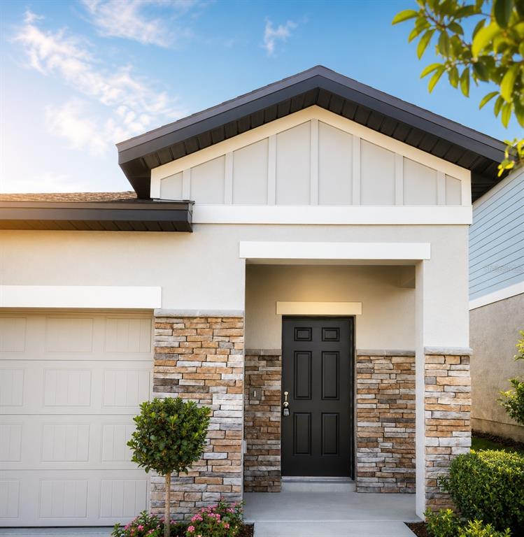 The exterior of a modern home features a black front door, stone veneer, and garage — 8731 SPORTSMAN LOOP, GROVELAND, FL