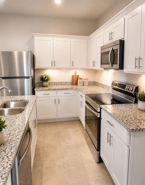 A kitchen features white cabinets, granite countertops, and stainless steel appliances — 8731 SPORTSMAN LOOP, GROVELAND, FL