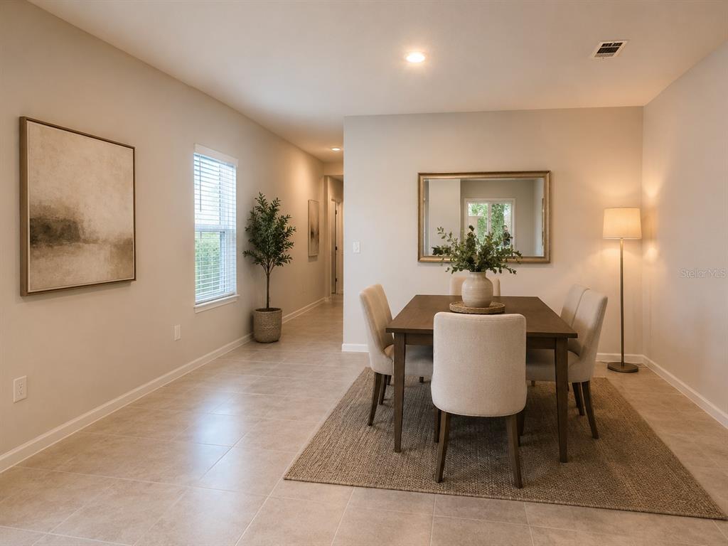 A dining room features a wooden table with four upholstered chairs on a textured rug — 8731 SPORTSMAN LOOP, GROVELAND, FL