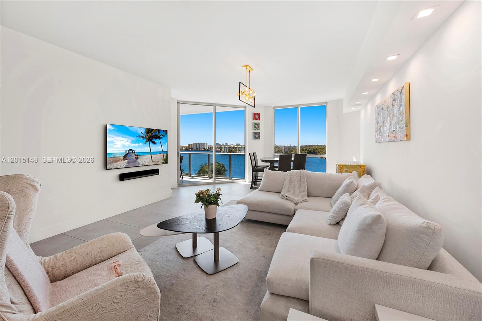 A modern living room features a white sectional sofa, a television, and floor-to-ceiling windows — 17111 Biscayne Blvd # 606, North Miami Beach FL 33160, NORTH MIAMI BEACH, FL