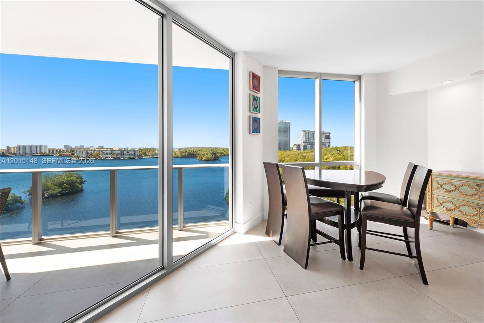 A dining area with a table, four chairs, and floor-to-ceiling windows overlooking a lake — 17111 Biscayne Blvd # 606, North Miami Beach FL 33160, NORTH MIAMI BEACH, FL