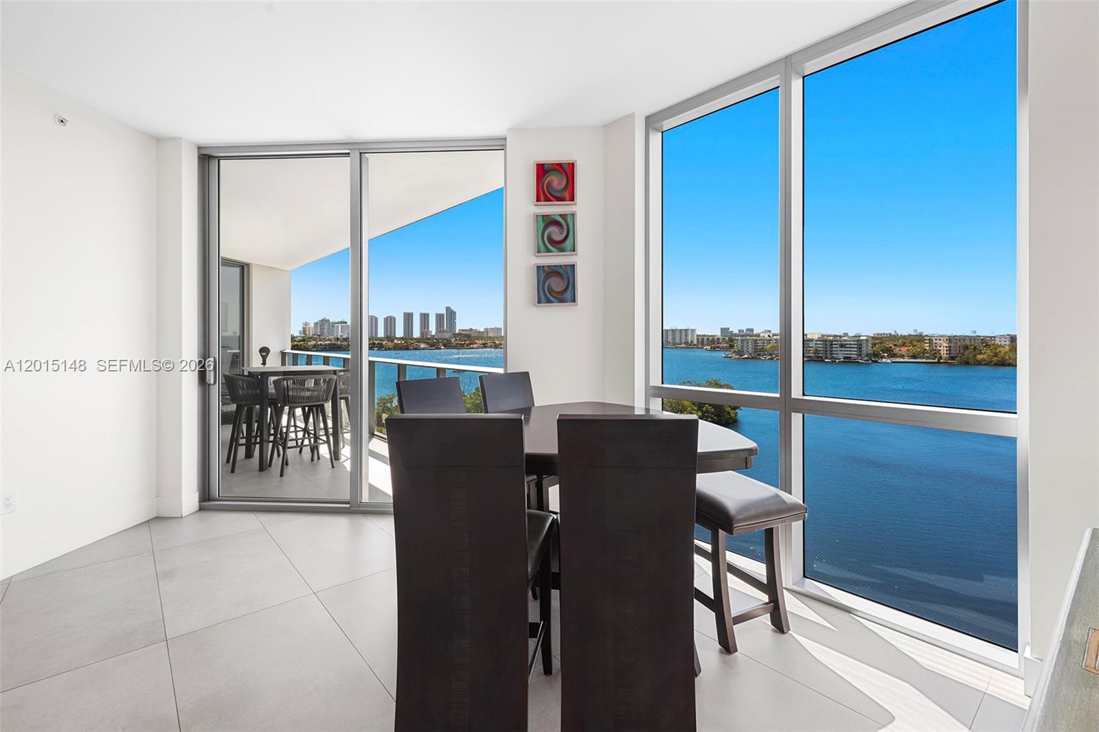 A dining area features a dark table and chairs with floor-to-ceiling windows overlooking water — 17111 Biscayne Blvd # 606, North Miami Beach FL 33160, NORTH MIAMI BEACH, FL