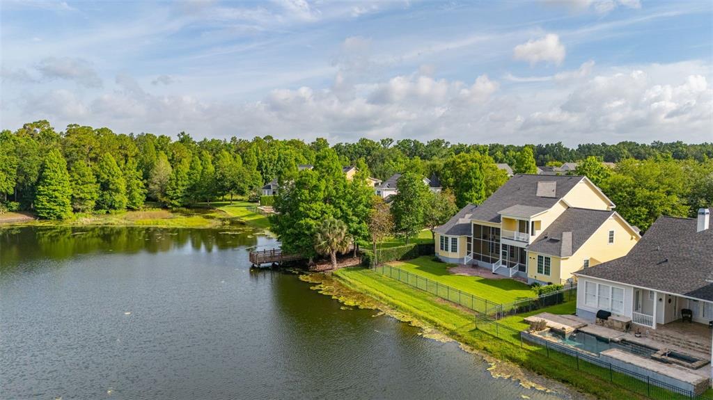 An aerial view shows two houses with backyards bordering a lake and a wooden dock — 1247 AQUILA LOOP, CELEBRATION, FL