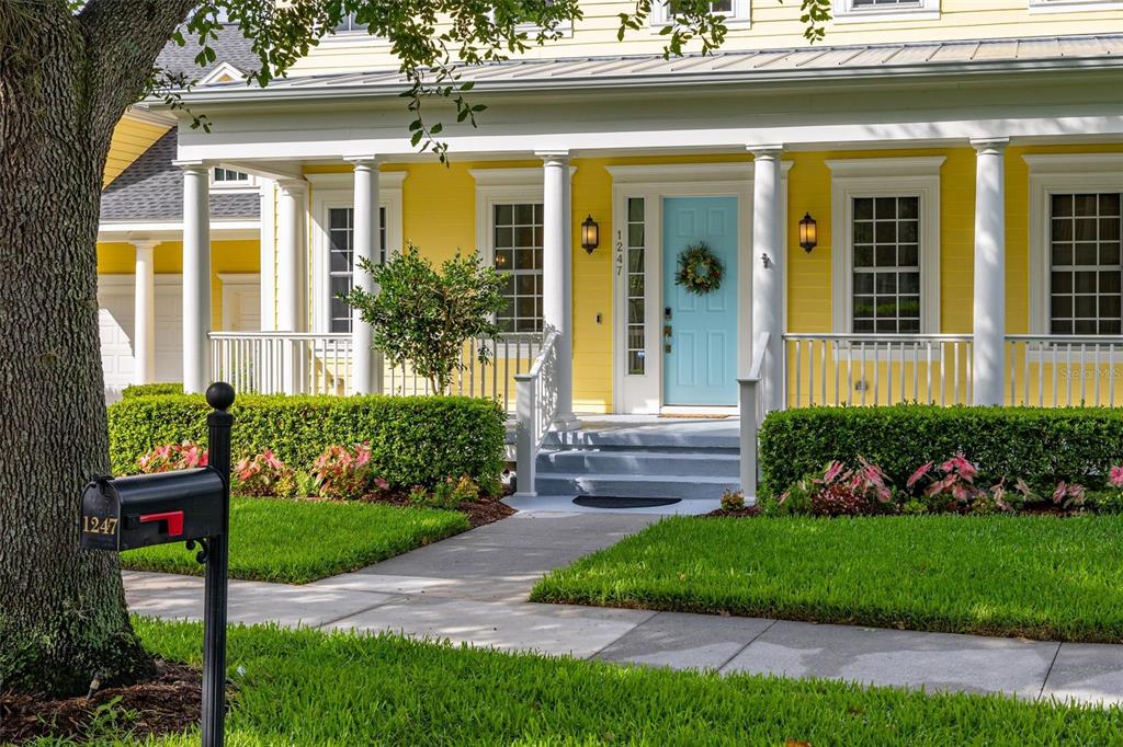 A yellow house with a light blue front door and a white porch — 1247 AQUILA LOOP, CELEBRATION, FL