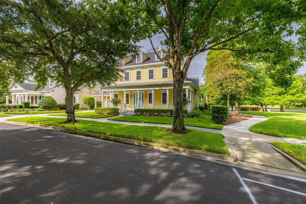 A yellow two-story house with a front porch and dormer windows sits on a street — 1247 AQUILA LOOP, CELEBRATION, FL