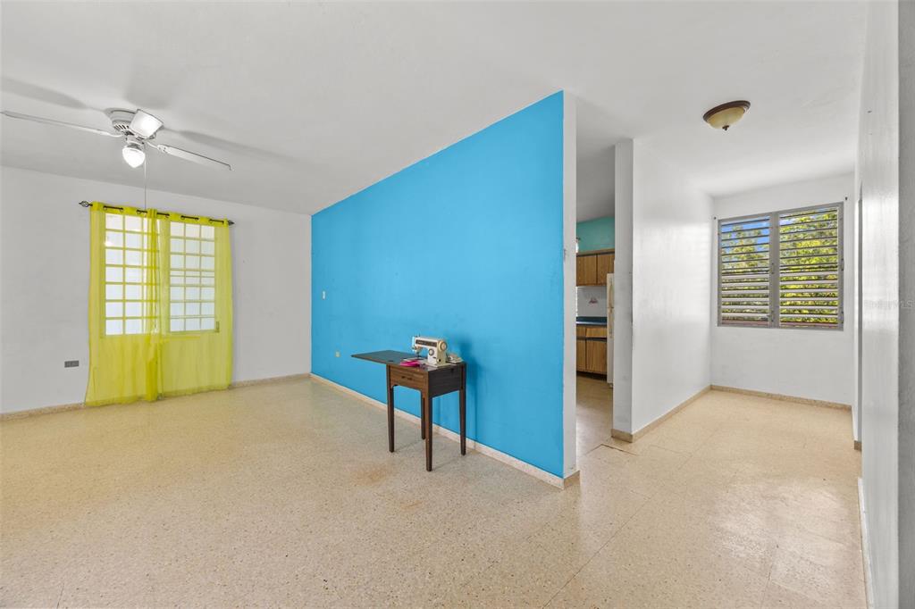 A living room features a bright blue accent wall, tile flooring, and a sewing machine table — Bo Cruces BO CRUCES, RINCON, PR