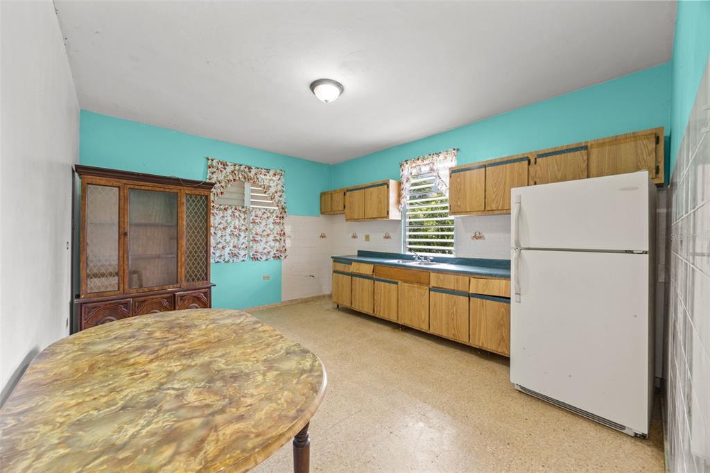 A kitchen features light wood cabinets, teal countertops, turquoise walls, and a white refrigerator — Bo Cruces BO CRUCES, RINCON, PR