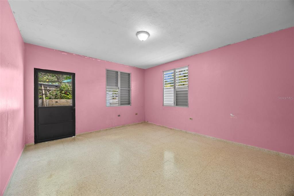 An empty room with pink walls, light-colored tile flooring, and two louvered windows — Bo Cruces BO CRUCES, RINCON, PR