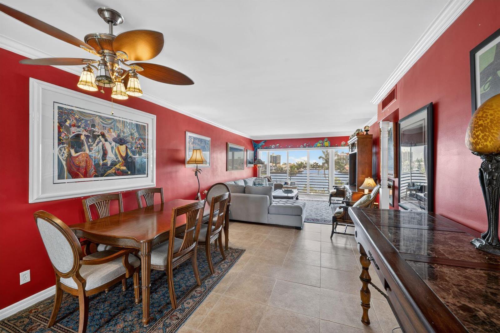 A dining area and living room with red walls, tile floors, and a waterfront balcony view — 3411 Spanish Trail # 418, Delray Beach FL 33483, DELRAY BEACH, FL