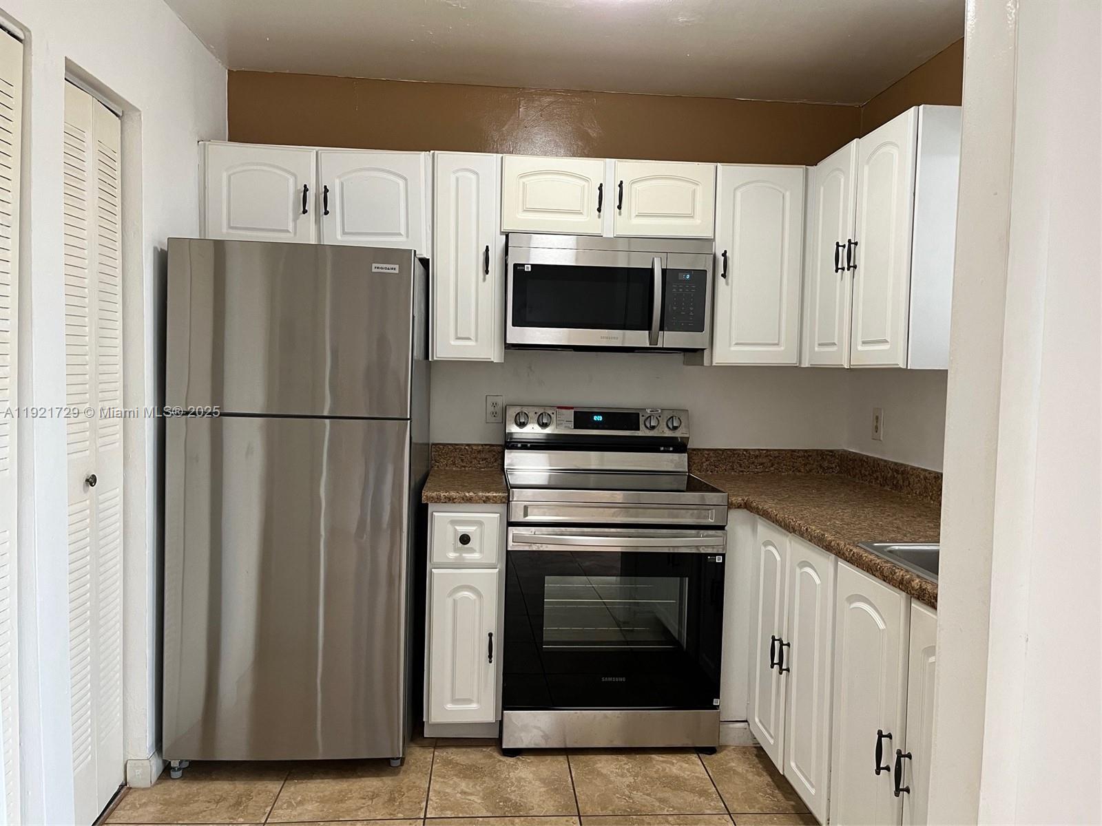 A kitchen features white cabinets, stainless steel appliances, and brown granite countertops — 13500 NE 3rd Ct # 402, North Miami FL 33161, NORTH MIAMI, FL
