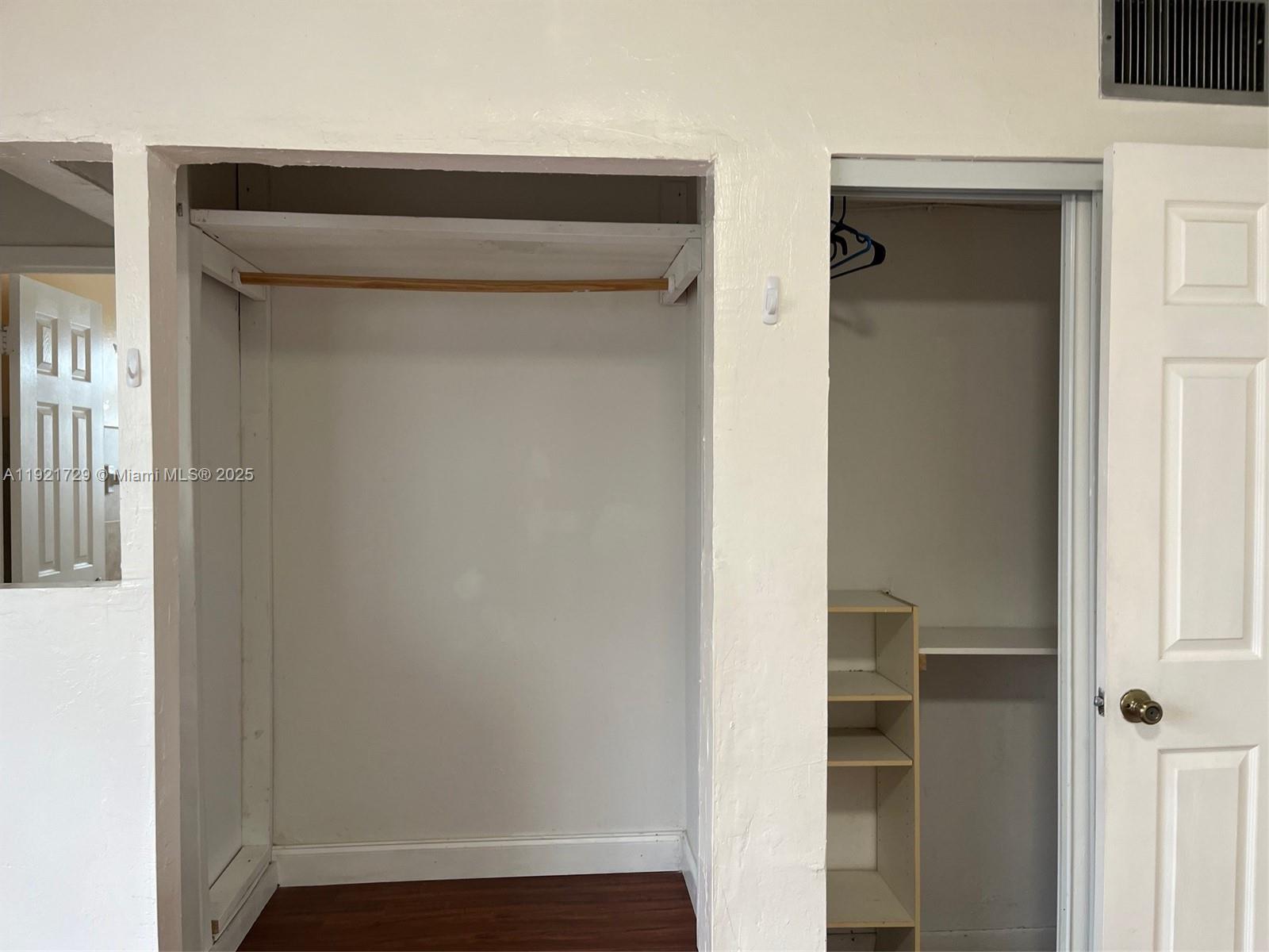 This image shows two adjacent closets with white walls, wooden flooring, and interior shelving — 13500 NE 3rd Ct # 402, North Miami FL 33161, NORTH MIAMI, FL