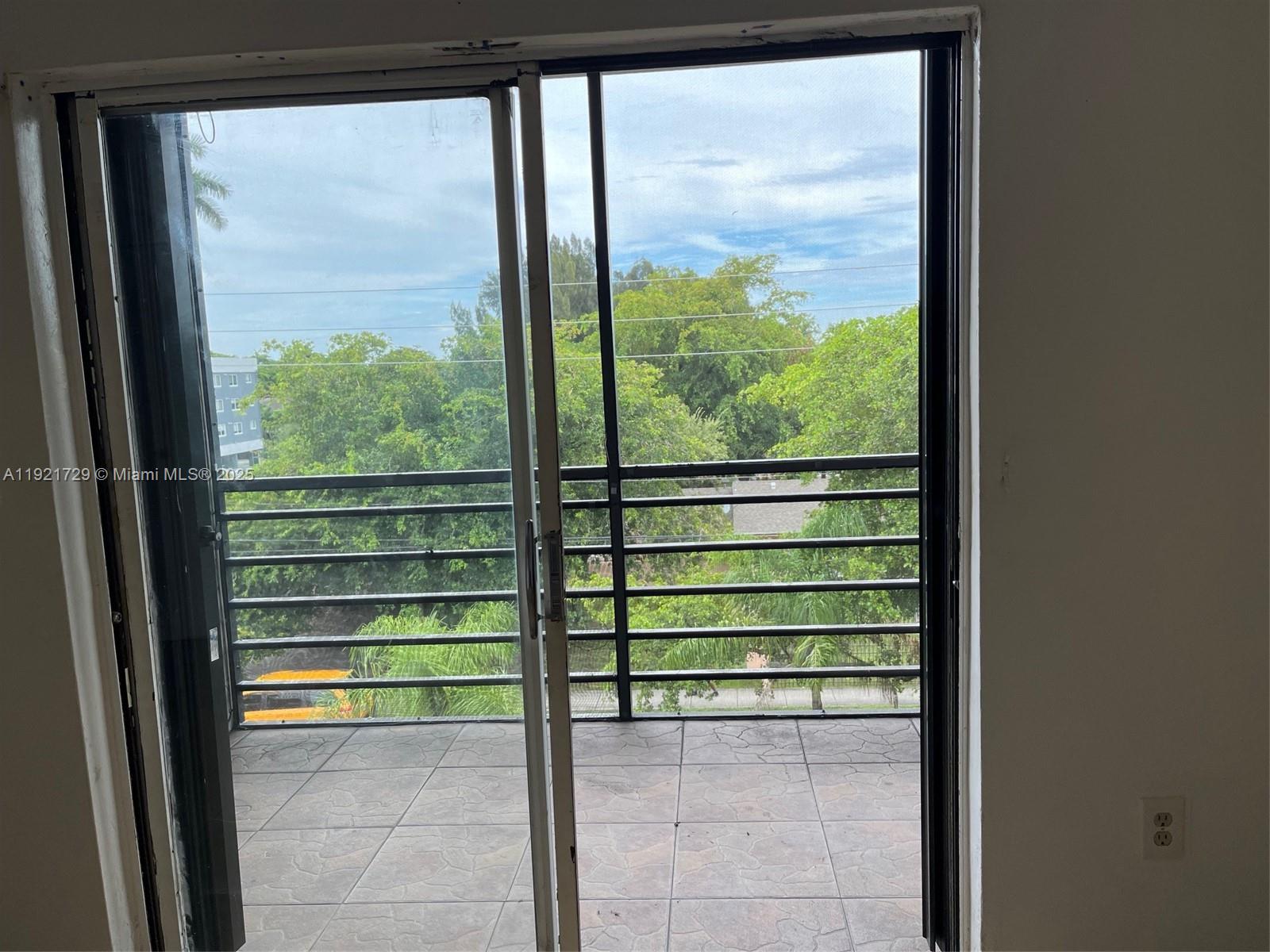 A sliding glass door opens onto a tiled balcony with a black metal railing — 13500 NE 3rd Ct # 402, North Miami FL 33161, NORTH MIAMI, FL