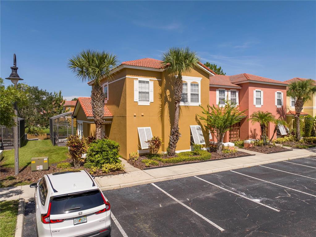 A white SUV is parked in front of two-story yellow and pink stucco townhomes — 122 POMPANO BEACH DRIVE, KISSIMMEE, FL