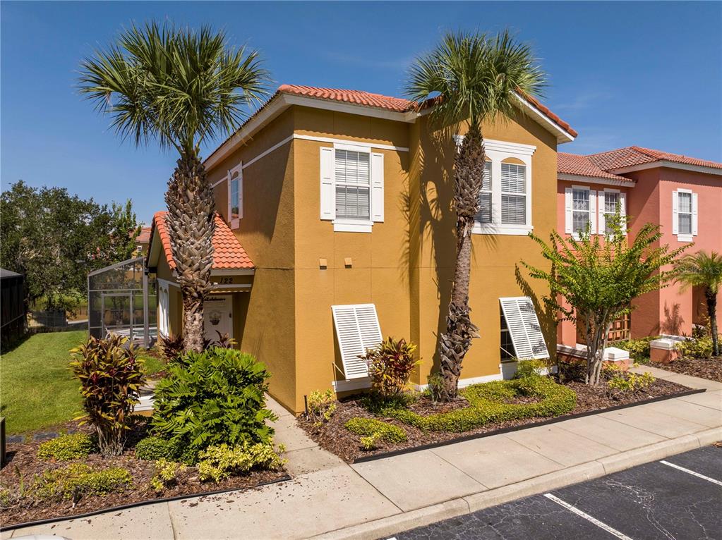 A two-story yellow stucco house with a tile roof and two palm trees in front — 122 POMPANO BEACH DRIVE, KISSIMMEE, FL