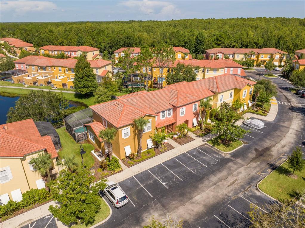 An aerial view shows a multi-unit residential building with orange tile roofs and parking spaces — 122 POMPANO BEACH DRIVE, KISSIMMEE, FL