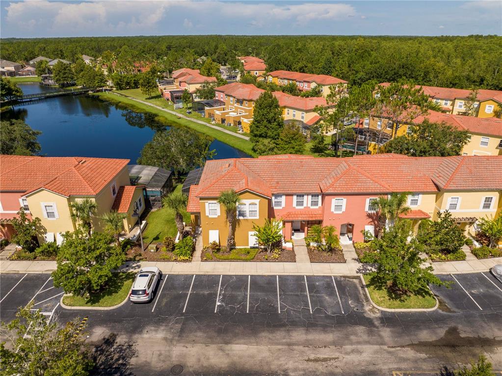 An aerial view shows a row of townhomes with red tile roofs near a pond — 122 POMPANO BEACH DRIVE, KISSIMMEE, FL
