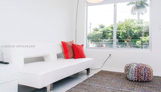 A white sofa with red pillows sits on a rug in a bright living room — 801 15th St # 208, Miami Beach FL 33139, MIAMI BEACH, FL