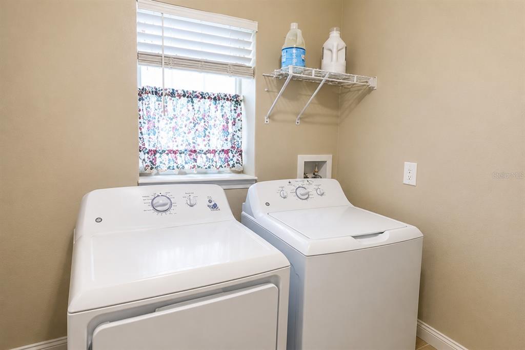 A laundry room features a white washer and dryer, a window, and a wire shelf — 15446 BROAD BRUSH DRIVE, RUSKIN, FL