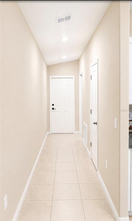 A narrow hallway features beige tile flooring, light-colored walls, and two white interior doors — 15446 BROAD BRUSH DRIVE, RUSKIN, FL