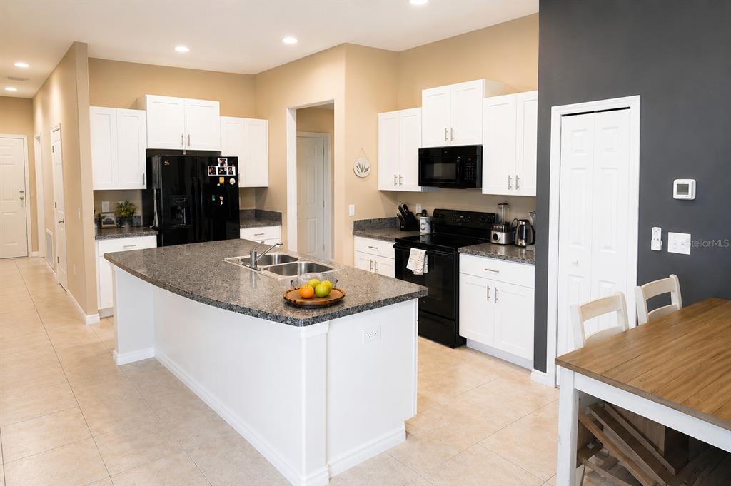 A kitchen with white cabinets, granite countertops, a central island, and black appliances — 15446 BROAD BRUSH DRIVE, RUSKIN, FL