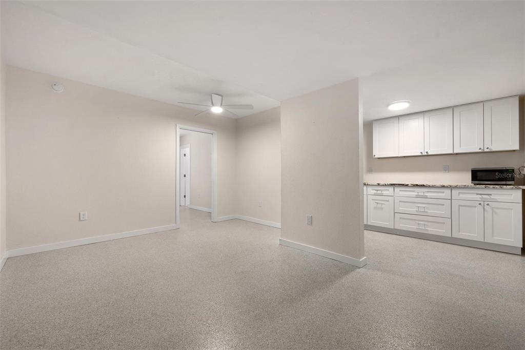 A room with light-colored walls and speckled flooring features a kitchen area with white cabinets — 308 OHIO PLACE UNIT 2, SARASOTA, FL