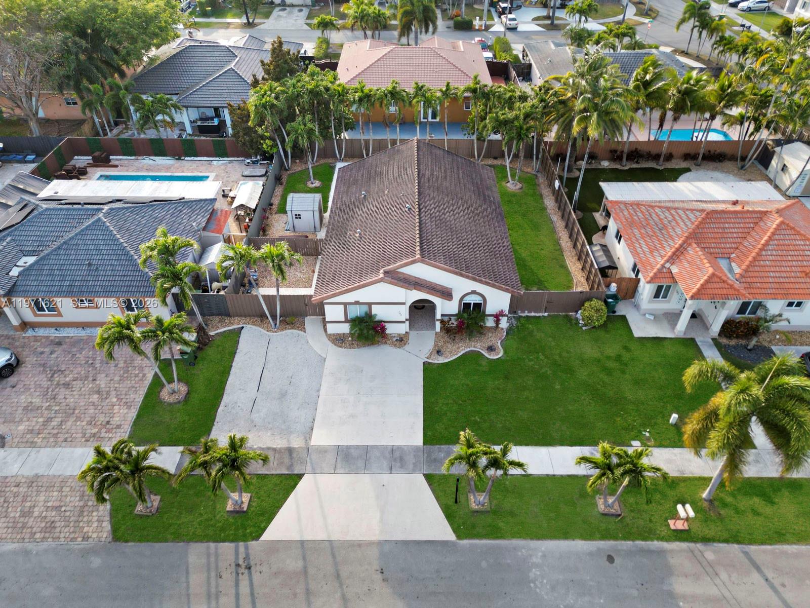 An aerial view shows a single-story house with a brown tile roof and palm trees — 704 SE 14th Pl, Homestead FL 33033, HOMESTEAD, FL