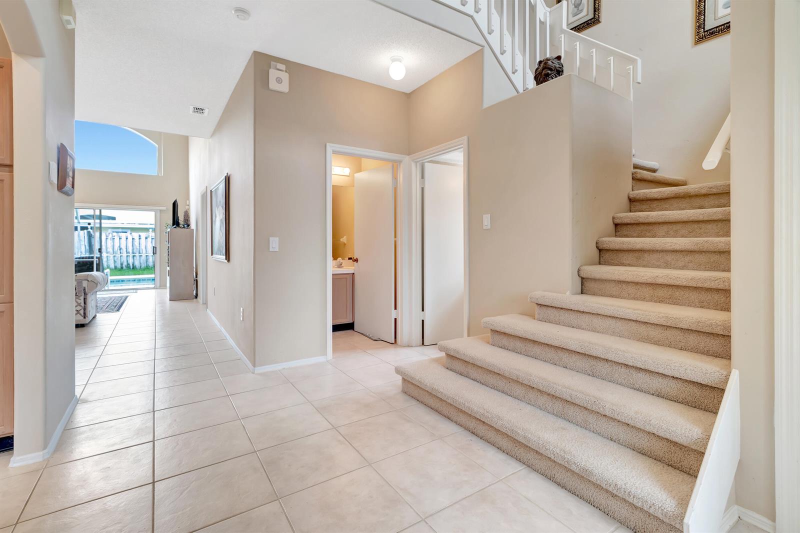 An entryway features beige tile flooring, a carpeted staircase, and two doorways leading to rooms — 2613 Spring Hill Drive, Kissimmee FL 34743, KISSIMMEE, FL