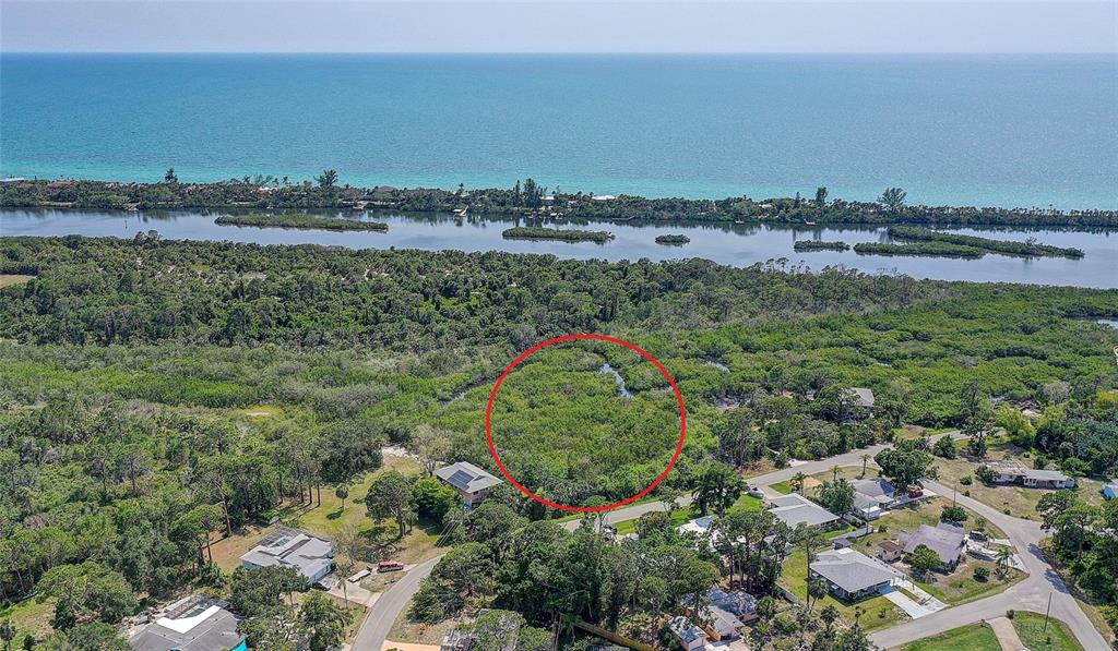 An aerial view shows a wooded lot circled in red near a coastal waterway — 0 LEMON BAY DRIVE, VENICE, FL