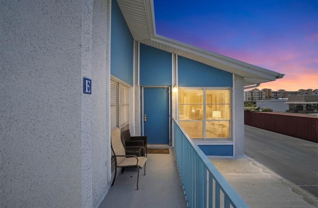 An exterior view of a balcony with a blue door, chairs, and a metal railing — 155 MEDALLION BOULEVARD UNIT E, MADEIRA BEACH, FL