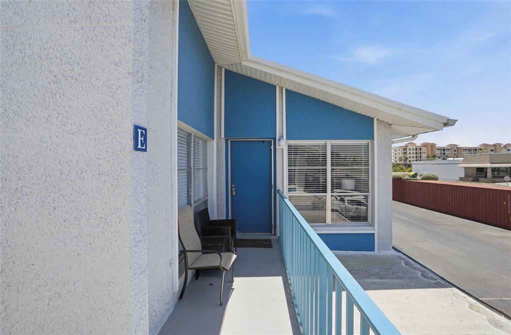 An exterior view of a balcony with a blue door, blue railing, and two chairs — 155 MEDALLION BOULEVARD UNIT E, MADEIRA BEACH, FL
