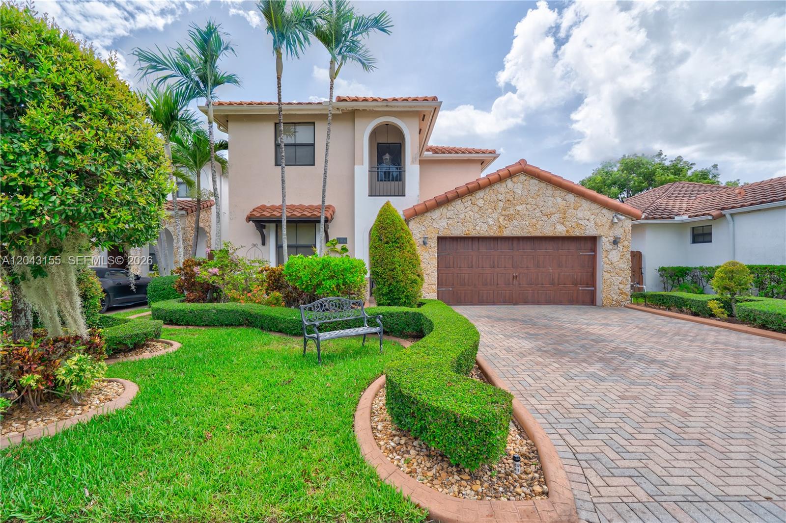A two-story house with a stone-accented garage, a paved driveway, and manicured landscaping — 1016 NW 99th Psge # 1016, Miami FL 33172, MIAMI, FL