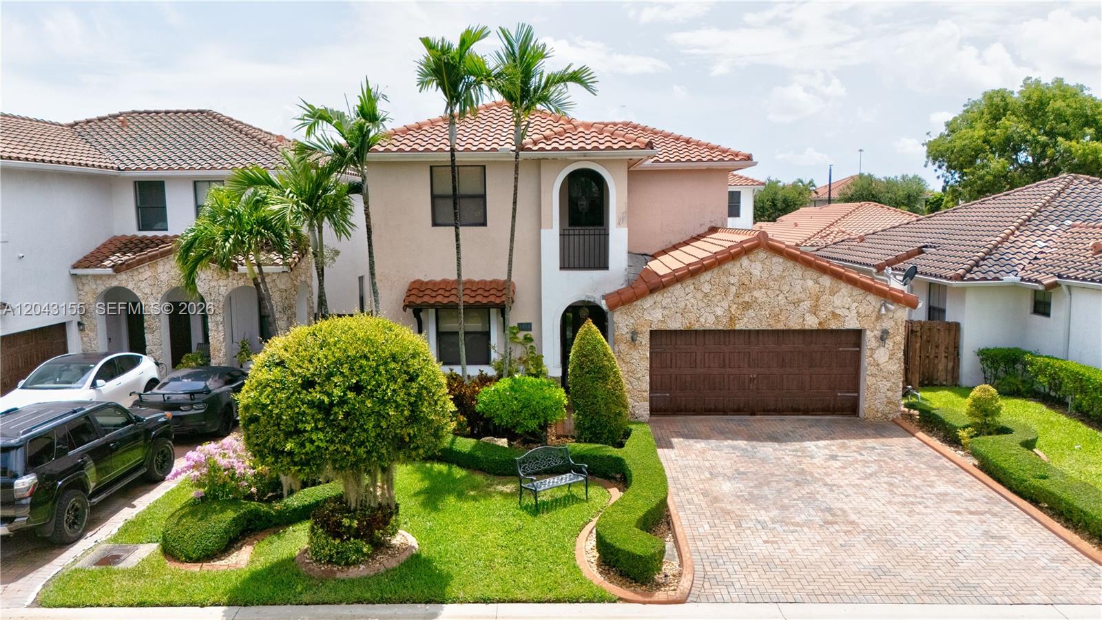An exterior view of a two-story house with a stone facade, tile roof, and driveway — 1016 NW 99th Psge # 1016, Miami FL 33172, MIAMI, FL