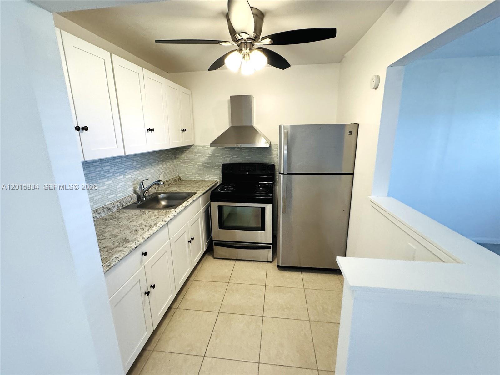 A kitchen features white cabinets, granite countertops, stainless steel appliances, and a ceiling fan — 138 Fanshaw # D, Boca Raton FL 33434, BOCA RATON, FL