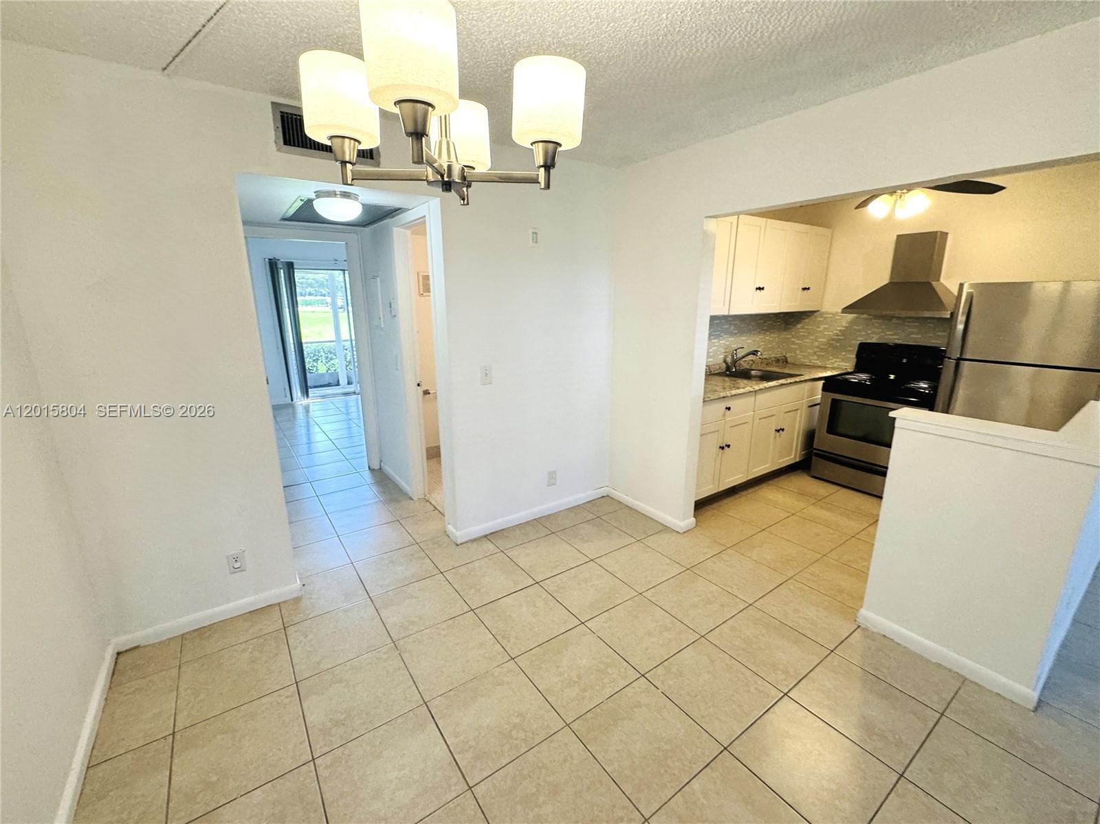 A dining area with tile floors leads to a kitchen and a hallway with balcony access — 138 Fanshaw # D, Boca Raton FL 33434, BOCA RATON, FL