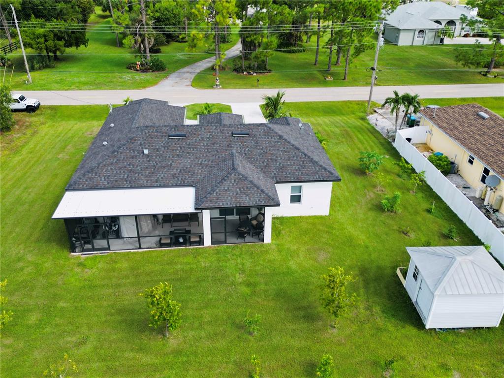 An aerial view of a house with a dark shingled roof and a screened-in patio — 528 JACARANDA PARKWAY E, CAPE CORAL, FL