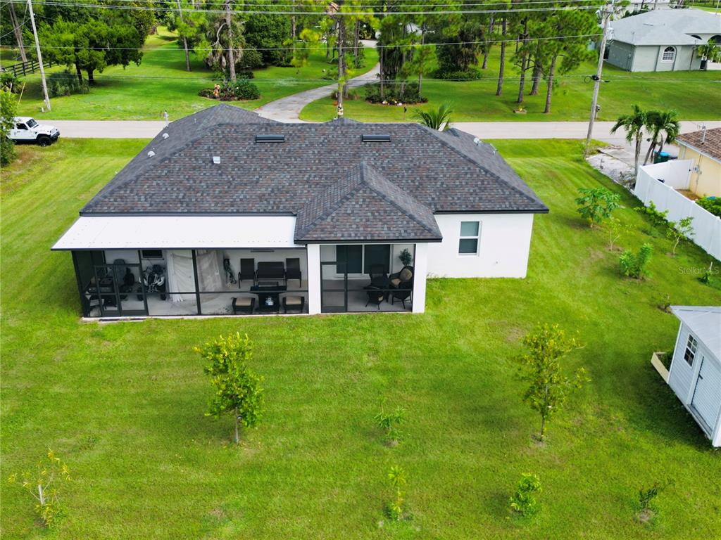 An aerial view of a single-story house with a screened-in back patio and yard — 528 JACARANDA PARKWAY E, CAPE CORAL, FL