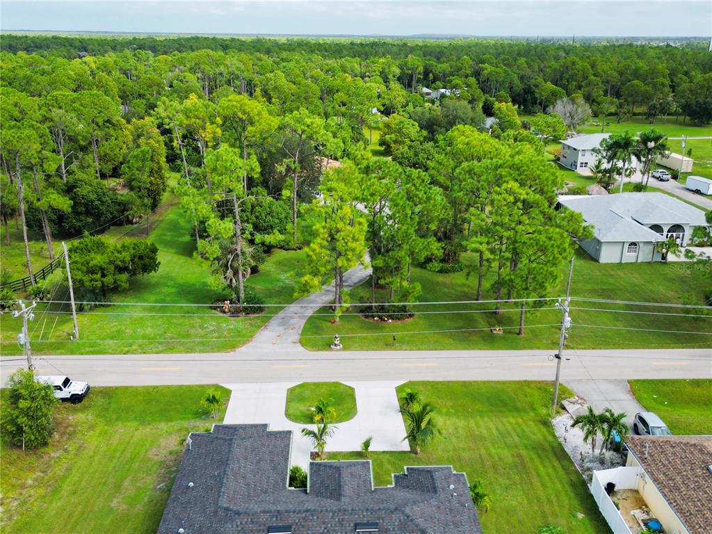 An aerial view shows a house with a driveway leading to a wooded lot — 528 JACARANDA PARKWAY E, CAPE CORAL, FL