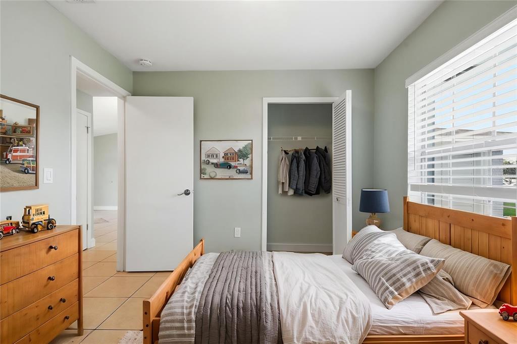 A bedroom with light green walls, a wooden bed frame, and a closet with hanging clothes — 2762 MYAKKA DRIVE, ORLANDO, FL