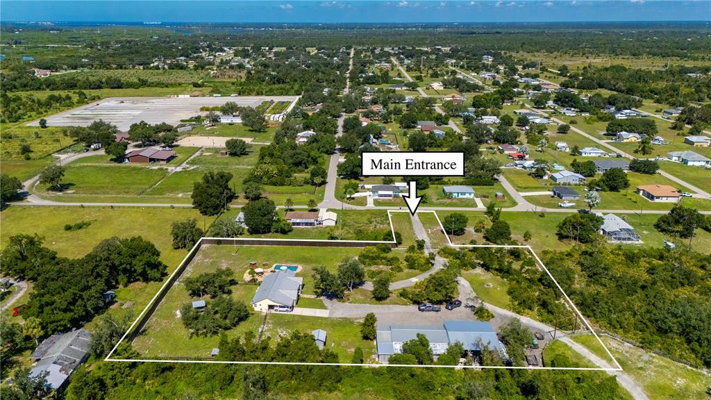 An aerial view shows a fenced residential property with two buildings, a driveway, and trees — 30941 TURKEY OAK ROAD, PUNTA GORDA, FL