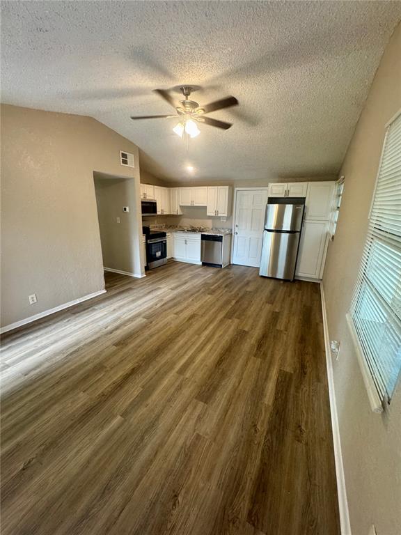 A kitchen and living area with wood-look flooring, white cabinets, and stainless steel appliances — 9216 W PATTERSON STREET, TAMPA, FL