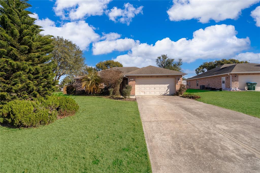 A single-story house with a beige garage and a concrete driveway under a blue sky — 794 SELBY STREET, DELTONA, FL