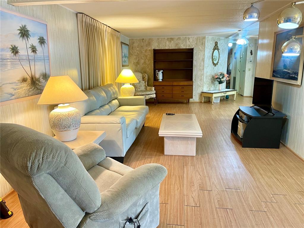 A living room features light wood-look flooring, a sofa, a recliner, and a wooden hutch — 5619 BAYSHORE ROAD UNIT 161, PALMETTO, FL
