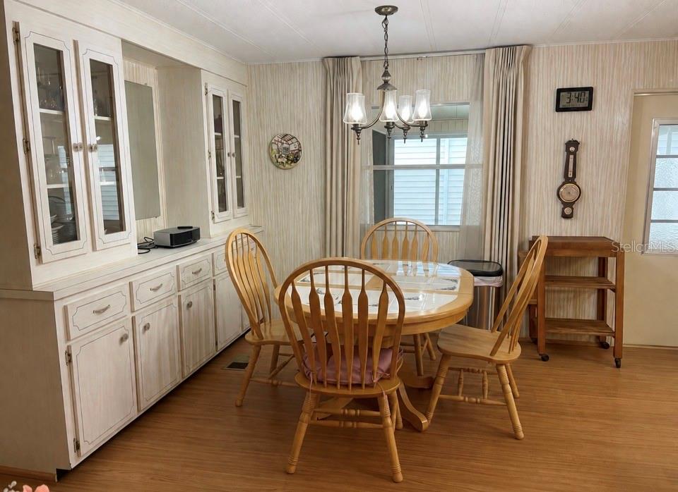 A dining room features a round wooden table, four chairs, a hutch, and light-colored wallpaper — 5619 BAYSHORE ROAD UNIT 161, PALMETTO, FL