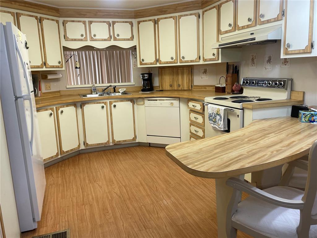 A kitchen features light-colored cabinets with wood trim, laminate countertops, and wood-look flooring — 5619 BAYSHORE ROAD UNIT 161, PALMETTO, FL