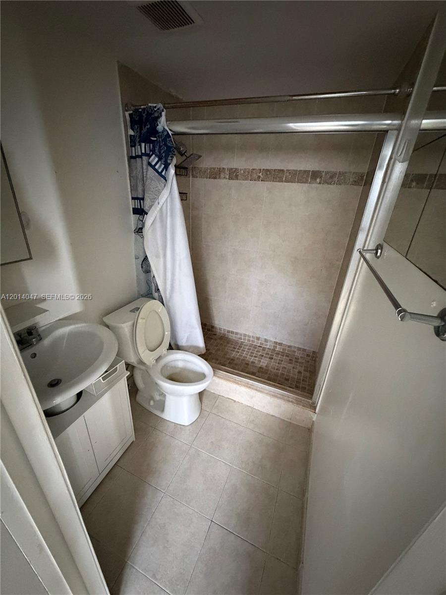 A small bathroom features a pedestal sink, a toilet, and a tiled walk-in shower — 1342 Drexel Ave # 205, Miami Beach FL 33139, MIAMI BEACH, FL