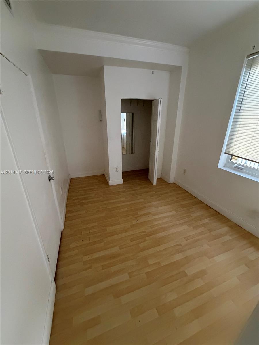 An empty room features light wood-look flooring, white walls, a window with blinds, and a closet — 1342 Drexel Ave # 205, Miami Beach FL 33139, MIAMI BEACH, FL