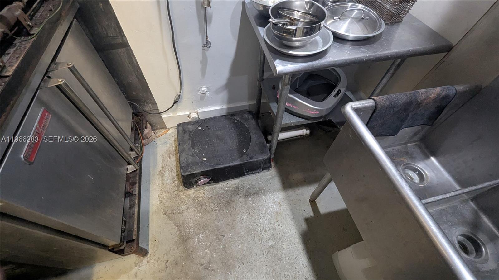 A commercial kitchen area features stainless steel equipment, a sink, and a floor grease trap — 1020 71st St # 106, Miami Beach FL 33141, MIAMI BEACH, FL