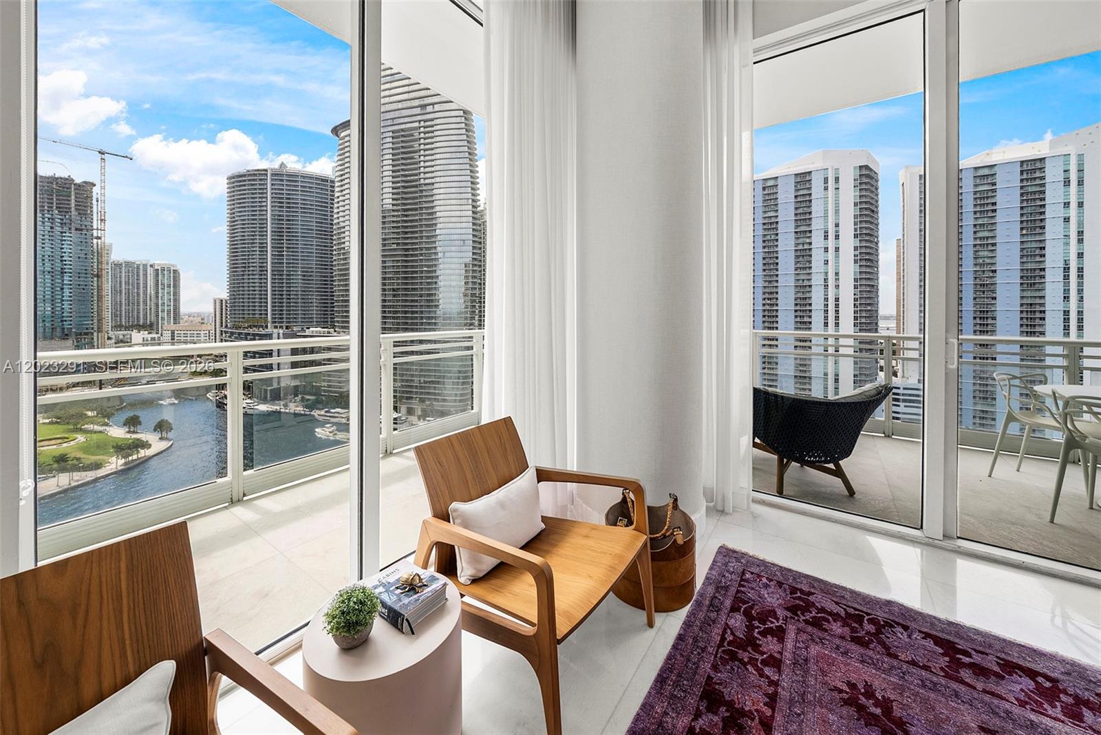 A modern interior room features floor-to-ceiling windows overlooking a city skyline and a river — 900 Brickell Key Blvd # 1801, Miami FL 33131, MIAMI, FL