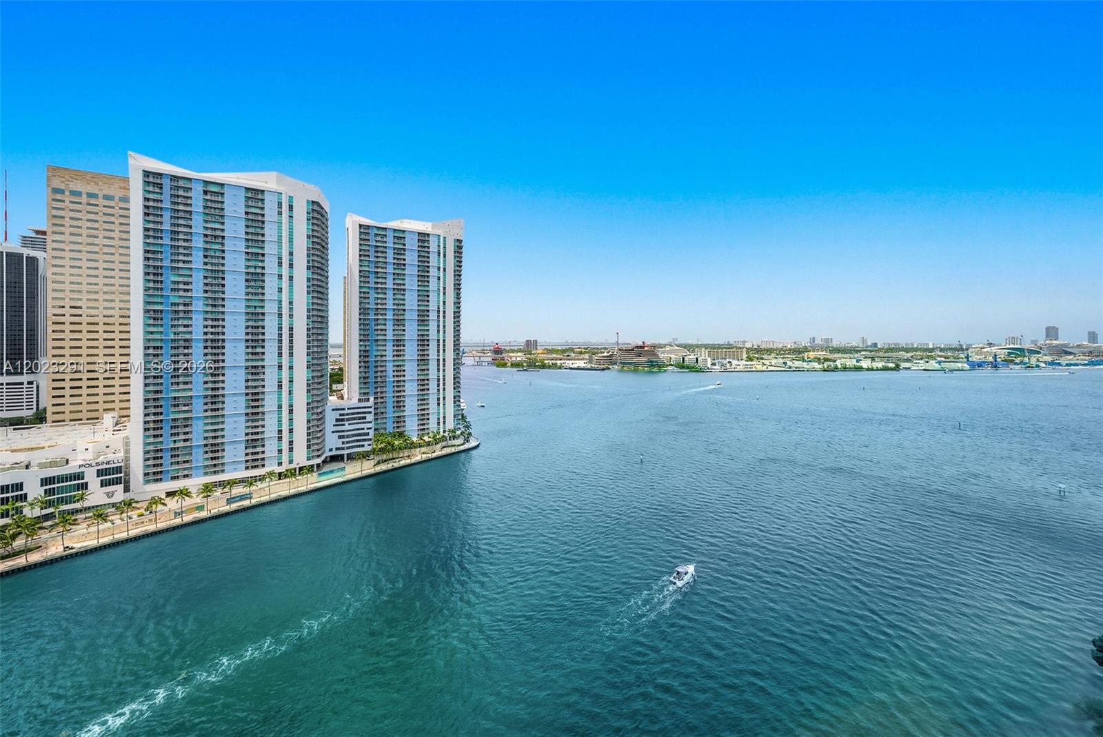 An aerial view shows high-rise apartment buildings along a waterfront with a boat nearby — 900 Brickell Key Blvd # 1801, Miami FL 33131, MIAMI, FL