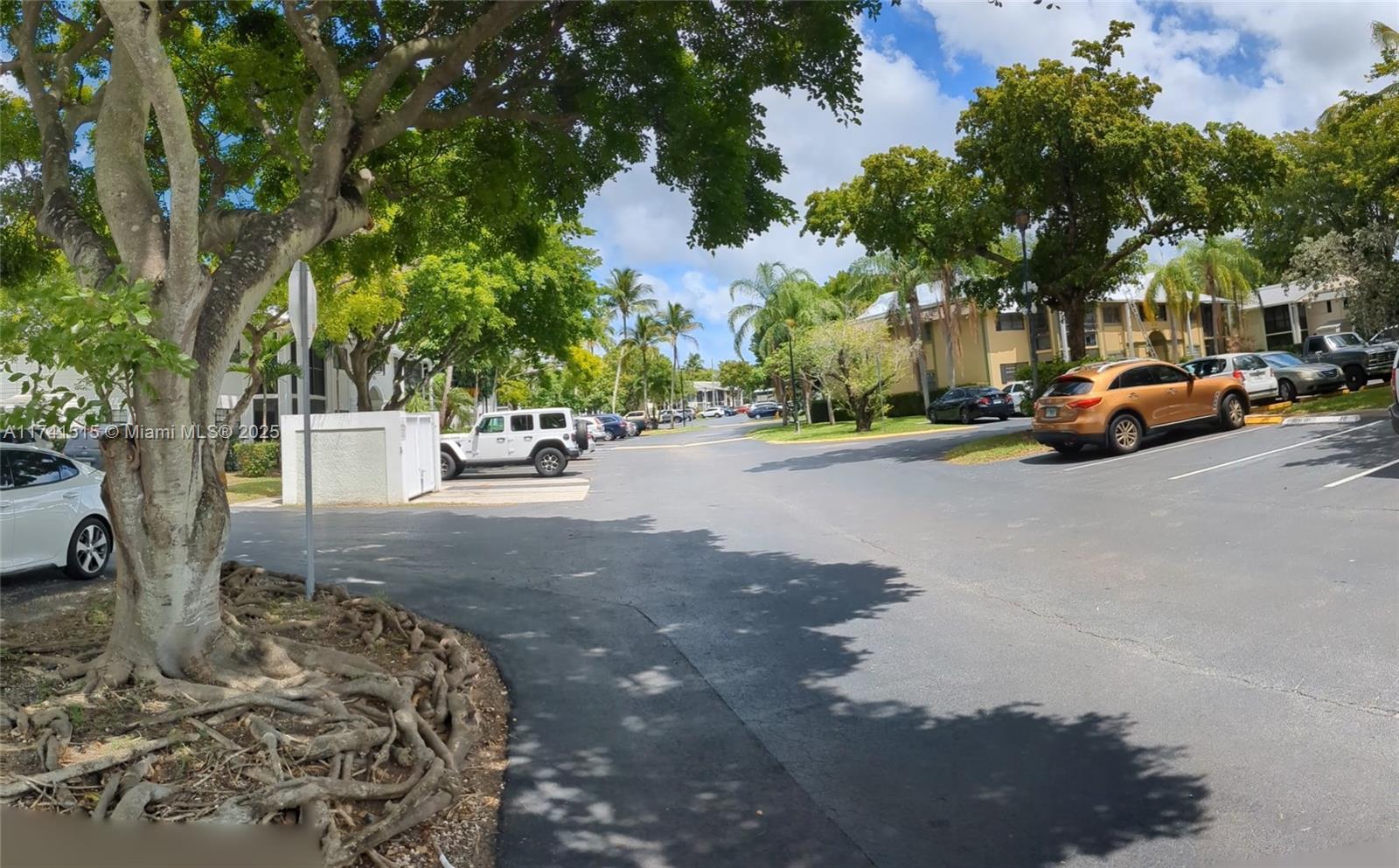 A paved parking lot with several parked cars surrounded by trees and residential buildings — 917 NE 199th St # 206, Miami FL 33179, MIAMI, FL